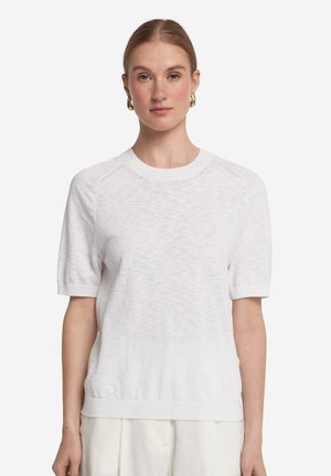 Pull en tricot blanc à manches courtes avec un col rond, présentant une finition texturée et des bords ribbées aux poignets et à l'ourlet.