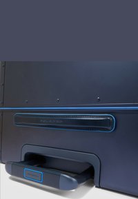 Valigia blu navy con esterno liscio e rigido. Presenta dettagli blu, una maniglia imbottita nera e un meccanismo estraibile per un facile trasporto.