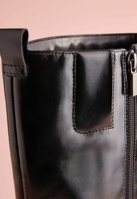 Czarne skórzane botki z zamknięciem na zamek, gładką fakturą i detalami przeszyć. Posiadają pętelkę na górze dla łatwego zakładania.