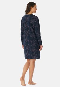 Abito blu navy con maniche lunghe, caratterizzato da un motivo floreale in rosa chiaro. Realizzato in un tessuto morbido, di lunghezza al ginocchio con una vestibilità comoda.