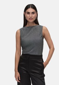 Ärmlös topp i metallgrå ribbad tyg med båturringning, kombinerad med högmidjade svarta satinsbyxor. Slät textur och åtsittande design.