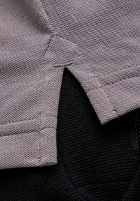 Brązowy tekstylny materiał o fakturowanym wykończeniu, z przeszytym mianem i bocznym rozcięciem, umieszczony obok czarnej tkaniny tkanej.