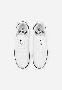 Baskets de sport blanches avec des accents noirs, présentant une tige en cuir lisse, un système de laçage et un col rembourré pour le confort. Taille 41.