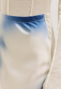 Satijnen rok met een ombre-effect, die overgaat van licht ivoor naar blauw bij de tailleband, met een soepele textuur en een discrete rits.
