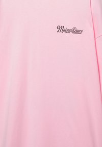 Camicia rosa chiaro con piccolo testo nero "Maison Douce 11e Arr. MARSEILLE" sul lato superiore sinistro del petto.