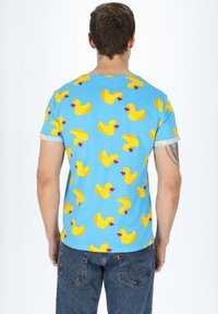 Sininen lyhythihainen t-paita, jossa on toistuva keltainen kumileluankka-kuvio. Puuvillamateriaali, jossa on pehmeä koostumus. Normaali istuvuus.