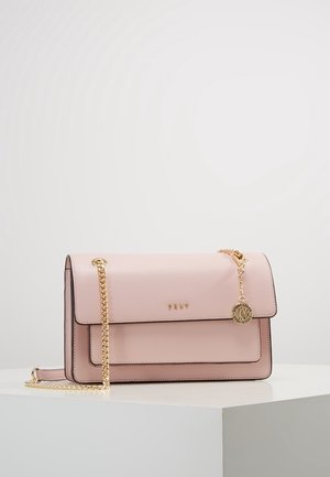 Sac à main rectangulaire rose doux avec bandoulière chaîne dorée, fermeture à rabat et petit pendentif rond doré avec gravure de la marque.