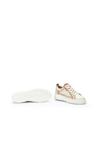 Zapatillas de cuero beige con suela de goma blanca, que presentan cordones, acentos laterales y una textura lisa. Lengüeta trasera en marrón.
