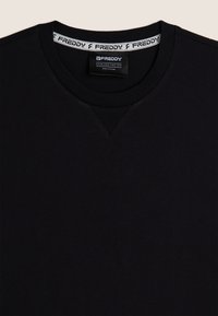 T-shirt nera in cotone con scollo rotondo, caratterizzata da un design a V discreto sulla parte anteriore e un'etichetta del marchio a contrasto all'interno del colletto.