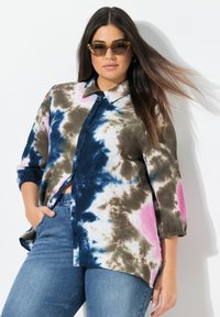 Camisa de botones con un estampado de tie-dye en azul, marrón y rosa. Presenta un cuello con solapa y mangas largas. Tejido texturizado.