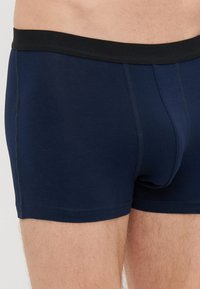 Marineblaue Baumwoll-Boxershorts mit einem schwarzen elastischen Bund, die eine enge Passform und Flachnahtnähte für Komfort und Langlebigkeit bieten.