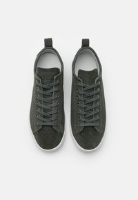 Dunkelgrüne Wildledersneaker mit runder Zehenpartie, flachen Schnürsenkeln und einer weißen Gummisohle; verfügen über eine Zuglasche an der Ferse für ein einfaches Anziehen.