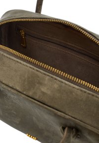 Oliivivihreä käsilaukku, jossa on tekstuuri pinta, kultainen vetoketju, ruskea sisävuori ja pieni vetoketjullinen tasku.