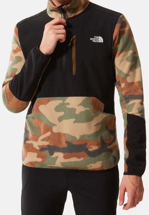 Mężczyzna w czarnym i moro polarowym pulowerze z półzamkiem i kieszenią na piersi, logo The North Face na lewej piersi.