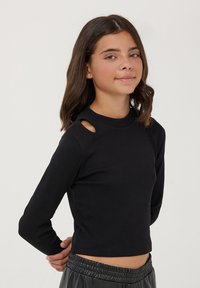 Czarny prążkowany top z długim rękawem i wycięciami na ramionach oraz wysokim kołnierzem. Dopasowany krój, krótsza długość i gładka tekstura.