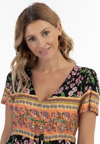 Rochie florală cu o bază neagră și accente în dungi portocalii și verzi, mâneci scurte și decolteu în V. Material texturat, ușor.