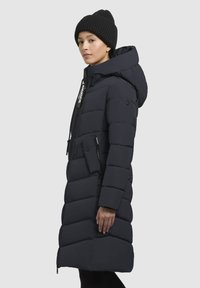 Manteau rembourré long bleu foncé avec capuche, présentant un motif matelassé, une fermeture éclair à l'avant, des cordons élastiques et deux poches latérales.