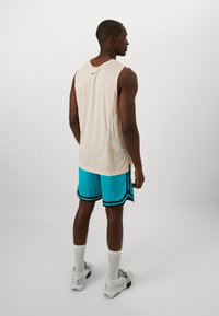 Nike spordiriided, mille hulka kuulub hele roosa võrkpoliesterist tank top ja türkiissinised lühikesed püksid mustade triipudega, lisaks valged sokid ja spordijalatsid.