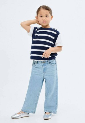 Un pull en tricot rayé bleu marine et blanc porté sur un t-shirt blanc, associé à un jean large bleu clair et des ballerines argentées.
