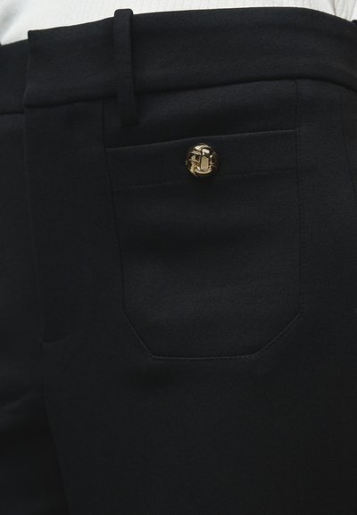 Pantaloni neri su misura con una texture liscia, caratterizzati da una singola tasca posteriore e un bottone decorativo dorato.