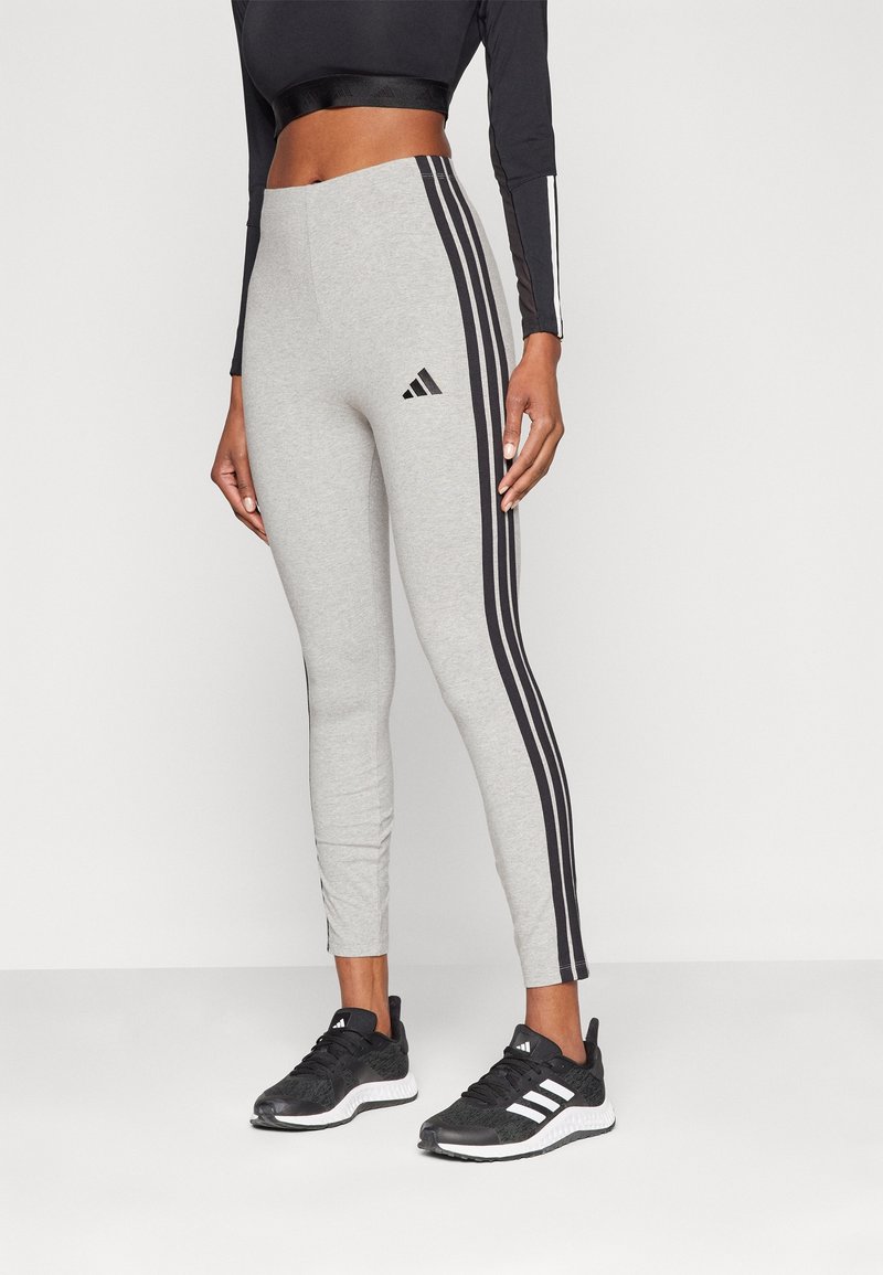 Grå leggings med svart tre-stripesdesign på sidorna, Adidas-logotyp på övre benet, tillverkad av ett stretchigt material för komfort.