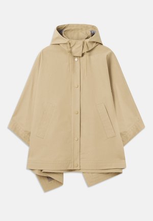 Béžová oversized pláštěnka s kapucí, zapínání na patentky, nastavitelné stahování a dvě přední kapsy; hladká, voděodolná tkanina.