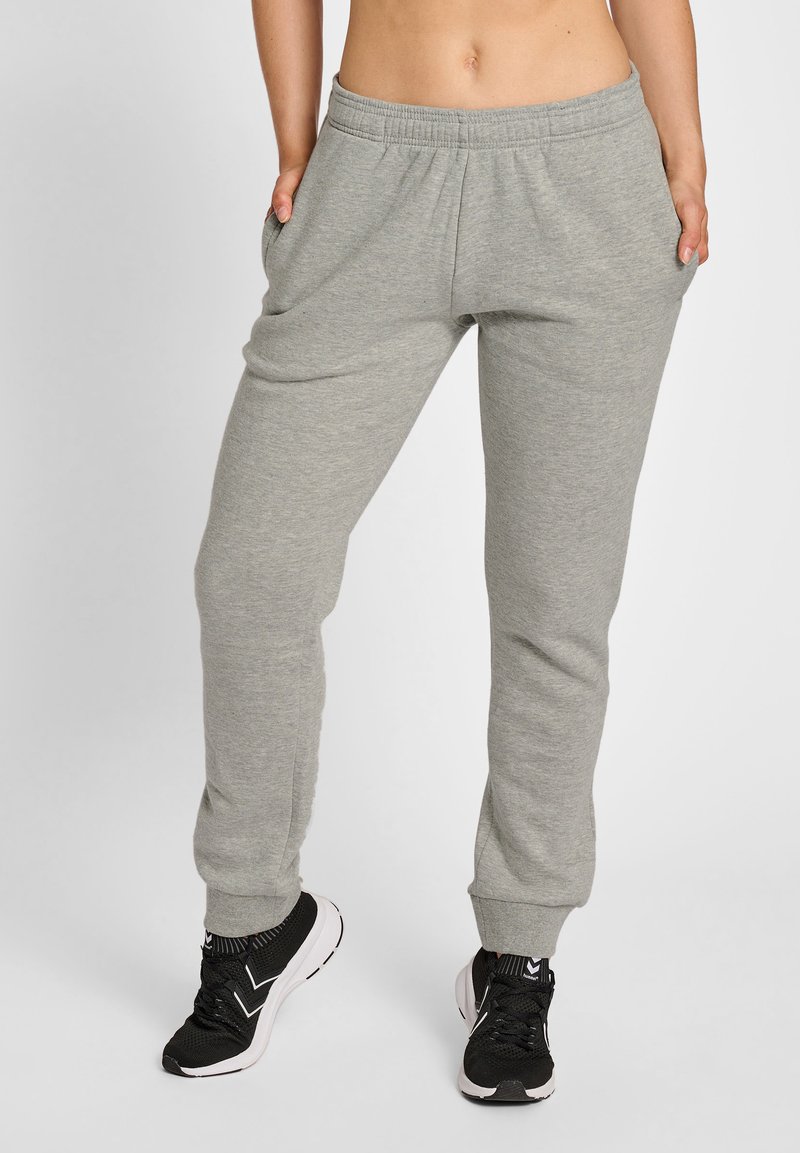 Grijze katoenen joggers met een elastische tailleband, zijzakken en taps toelopende boorden, gecombineerd met zwarte sportschoenen.
