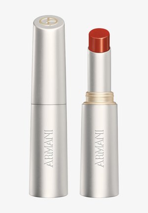 Tube de rouge à lèvres Armani argenté avec le nom de la marque, capuchon fermé à gauche, et rouge à lèvres corail-rouge assorti étendu à droite.