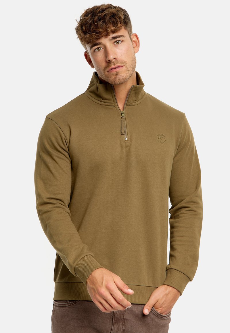 Sudadera de color verde oliva con media cremallera, confeccionada con tejido texturizado, con puños y dobladillo acanalados, y con un pequeño logo en el pecho.