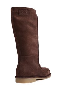 Brune semskede knestøvler med rund tå, flad sål og kontrasterende syninger. Har et mærket patch øverst.