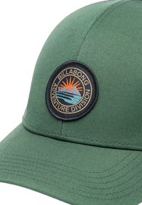 Green cap made of textured fabric, featuring a round patch with a sun, mountain, and waves in orange, blue, and black, labeled "Billabong Adventure Division."