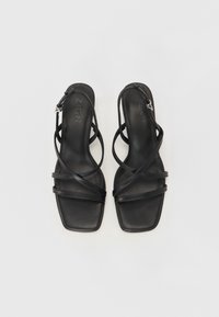 Black leather heeled sandals with multiple crisscross straps, square toe design, and an adjustable ankle strap with silver hardware.