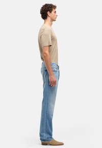 T-shirt beige a maniche corte, jeans azzurri a gamba dritta e stivaletti color cuoio. Design semplice, texture morbida e senza motivi visibili.