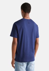 Tyrkysové bavlněné tričko s krátkými rukávy, vroubkovaným kulatým výstřihem a diskrétním logem vyšitým na horní části zad. Standardní střih, jednoduchý design.