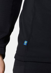 Black long-sleeve shirt with textured fabric, featuring a stitched seam design and a small blue-yellow Swedish flag accent on the hem.