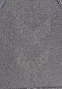 Zbliżenie na szary, teksturowany materiał z dwoma uniesionymi wzorami chevronu skierowanymi w dół w centrum.