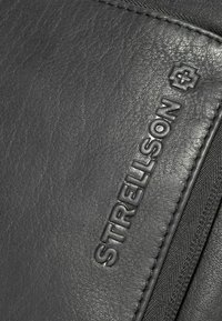 Borsa in pelle nera con superficie testurizzata, presenta il logo "Strellson" in rilievo e dettagli con zip, enfatizzando il design minimalista.