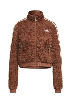 Veste Adidas en velours matelassé marron avec fermeture éclair complète, col montant, poches latérales zippées, poignets côtelés, et détails blancs à trois bandes sur les manches.