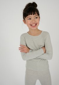 Maglietta a maniche lunghe grigio chiaro e leggings abbinati, realizzati in un morbido tessuto testurizzato. Il top ha un collo rotondo e un design semplice.