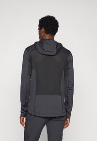 Black hoodie with textured mesh back, long sleeves, and adjustable hood. Smooth fabric with contrasting panel detailing. Suitable for active wear.