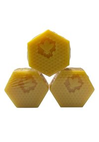 Three hexagonal blocks of yellow beeswax, featuring a honeycomb texture and embossed bee designs on the surface, each wrapped in clear plastic.