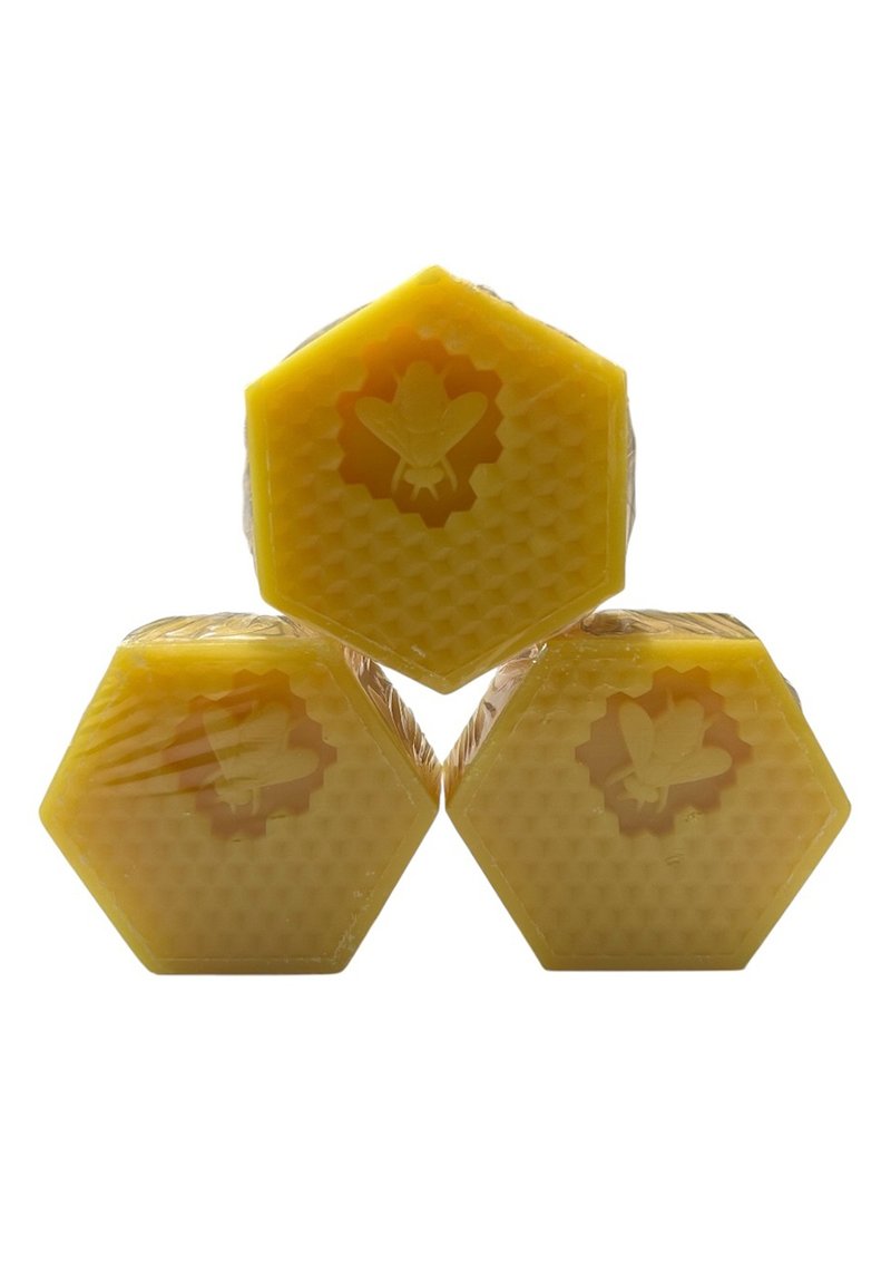 Three hexagonal blocks of yellow beeswax, featuring a honeycomb texture and embossed bee designs on the surface, each wrapped in clear plastic.