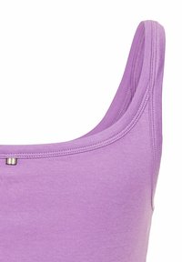 Lilla tanktop med rund halsudskæring, lavet af blødt, glat stof; har tynde stropper og en lille dekorativ detalje.