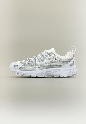 Chaussure de running Nike blanche et grise avec tige en mesh, fermeture à lacets, semelle amortie et languette au talon, vue de profil sur fond neutre.