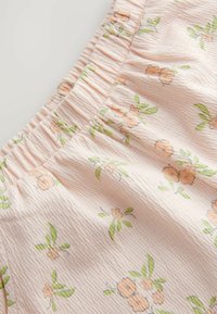 Blødt lyserødt stof med lille orange blomsterprint og grønne blade, med en indsamlet, elastisk talje.