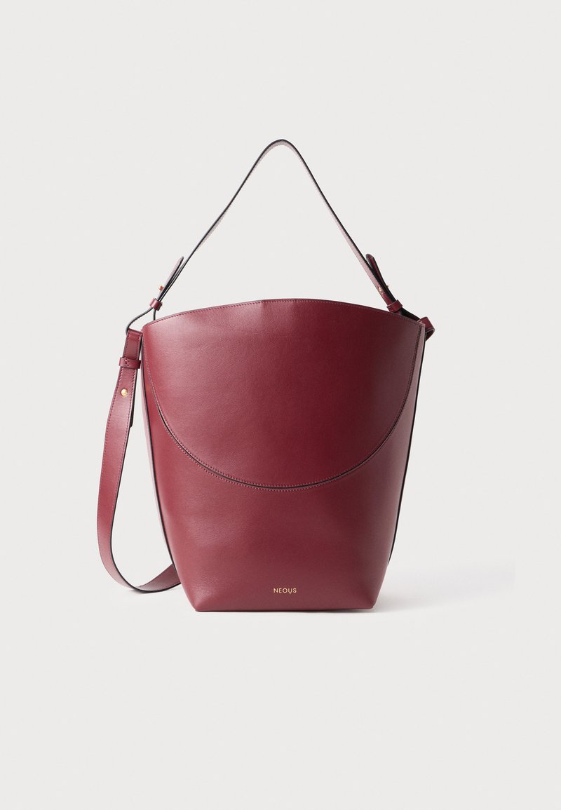 Borsa a secchiello in pelle bordeaux con finitura liscia, tracolla regolabile e discreto logo dorato nella parte inferiore. Forma superiore curva.