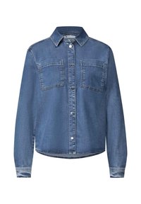 Chemise en denim bleu à manches longues avec fermeture boutonnée devant et deux poches poitrine, présentée sur fond blanc.