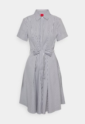 Robe à manches courtes avec col, rayures verticales noires et blanches, boutonnée sur le devant et ceinture nouée à la taille.