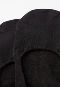 Schwarze Knöchelsocken mit glatter Textur, ausgestattet mit einem abgerundeten oberen Rand und elastischen Öffnungen für einen sicheren Sitz.