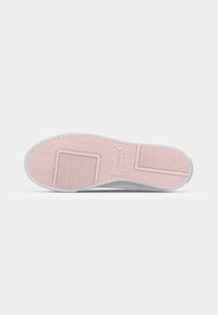 Semelle extérieure de sneaker blanche avec une semelle en caoutchouc rose texturé, dotée d'un motif en chevrons et d'un logo en relief pour une adhérence optimale et un design élégant.